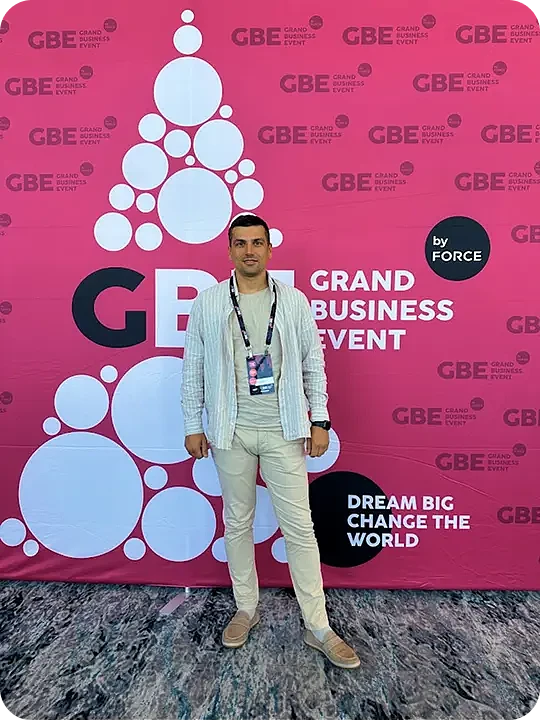 Webdelo representative in front of the Grand Business Event 2024 banner